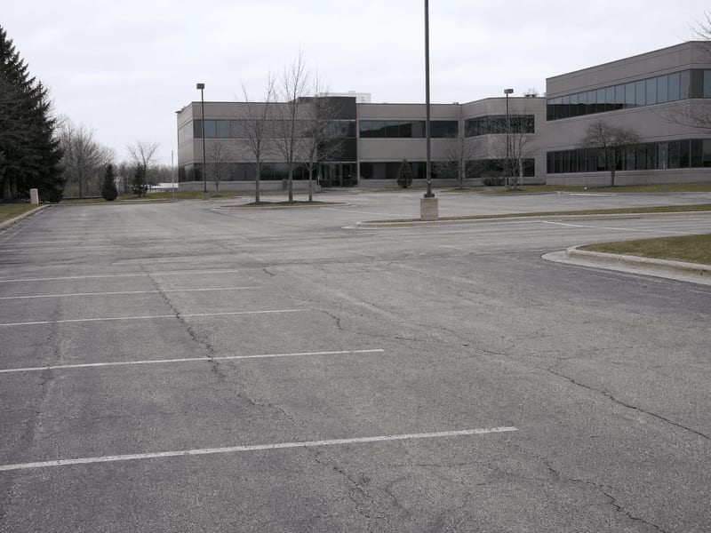 Ashwaubenon office park lot before sealcoating, showing graying asphalt